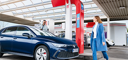 Frau auf dem Weg zu ihrem Auto an einer Esso-Tankstelle.